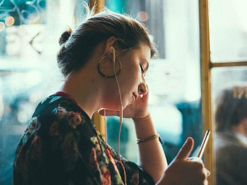 Girl getting text outside with earbuds