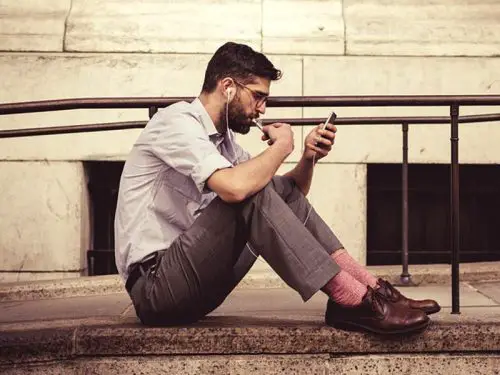 Man using phone on ground with earbuds